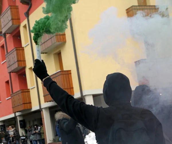 Protest with protesters dressed in black robes with green smoke