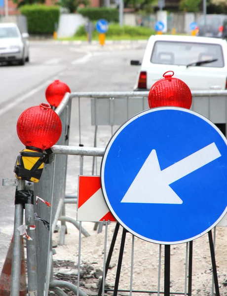 Narrowing of the roadway with red signal lamps and a road sign t