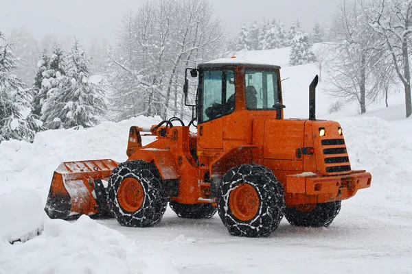 Orange snow plows to work clearing the snow from the road