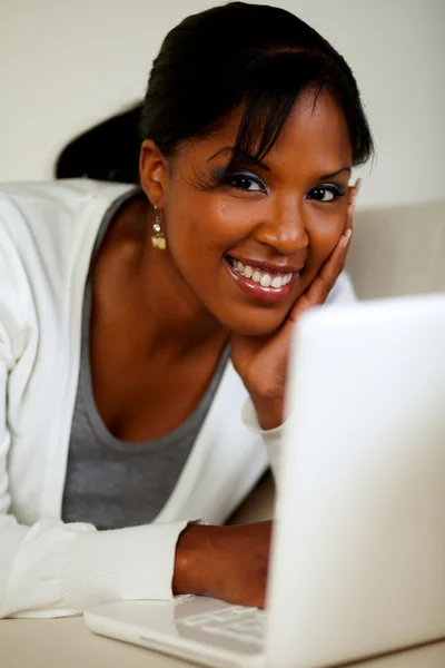 Young woman looking at you in front of her laptop