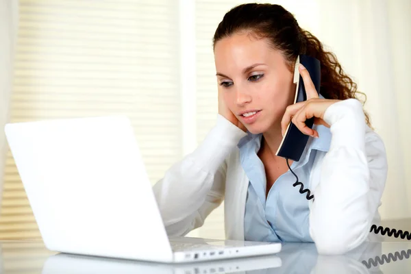 Tired young woman with headache speaking on phone