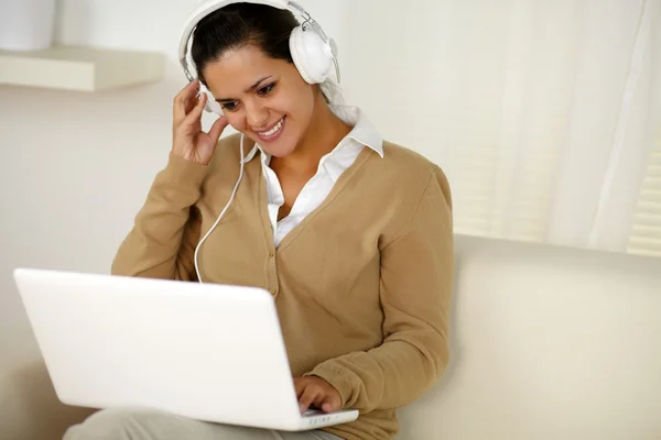 Young female with headphone reading laptop screen