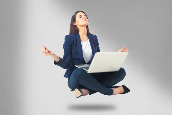 Young businesswoman sitting in yoga lotus position with laptop computer