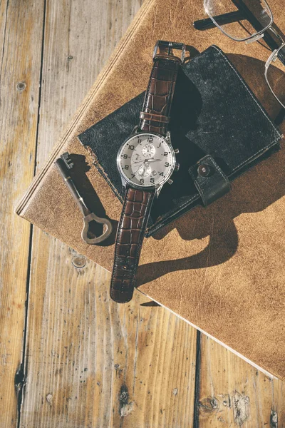 Man wristwatch, calendar, key and glasses on a old table.
