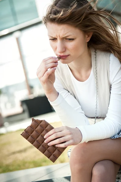 Depressed young woman eating chocolate