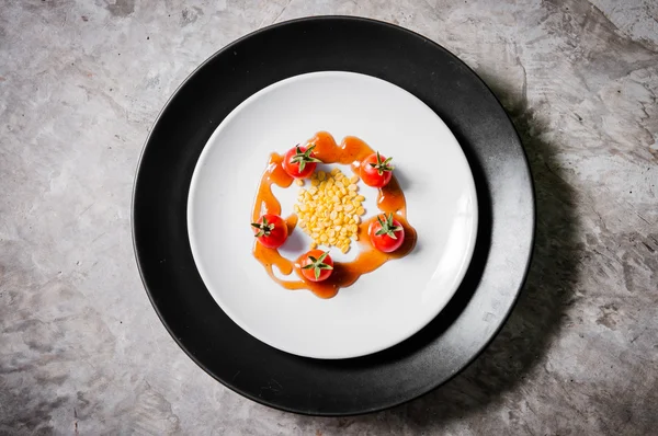 Small tomato and beans on white dish of bio food stylish