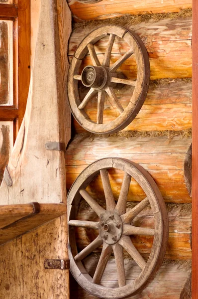 Village composition. Wooden wheels hanging on a wall of log house