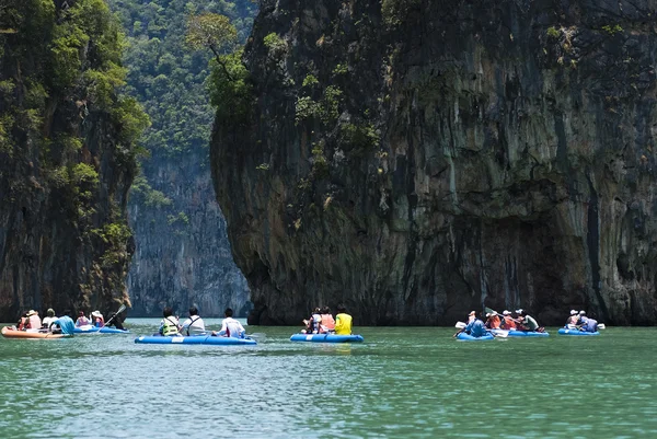 Tourists kayak through limestone cliffs
