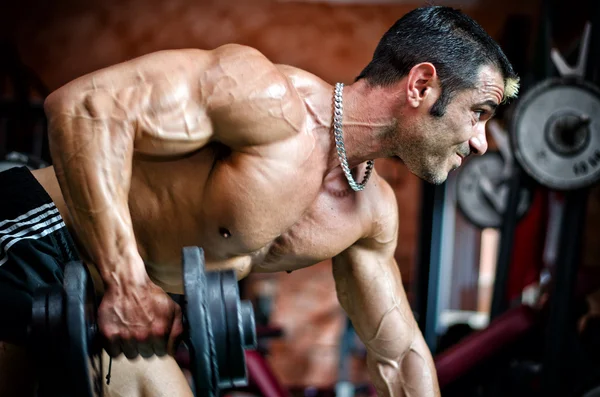 Muscular male bodybuilder working out in gym, exercising triceps