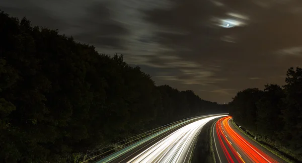 Long time exposure freeway cruising car light trails streaks of light speed highway moon cloudy