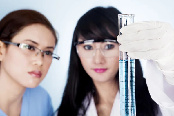 Female scientific research team with clear blue solution in laboratory