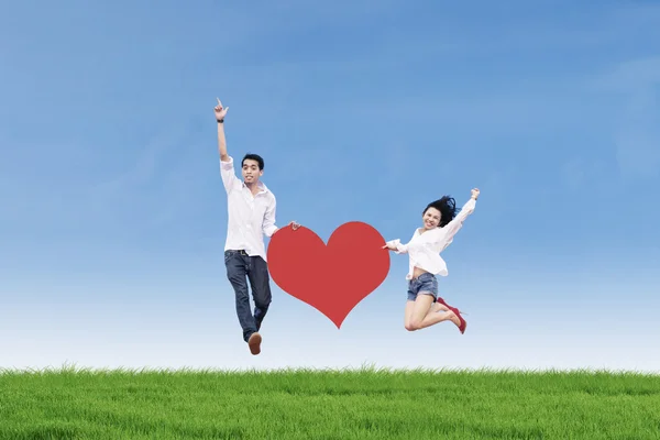 Couple jumping with heart card