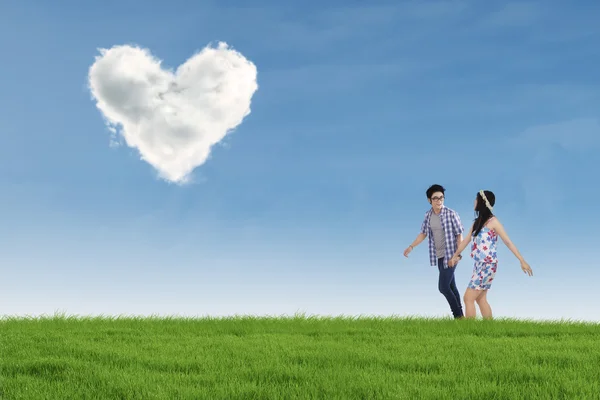Romantic couple with heart shaped cloud in nature