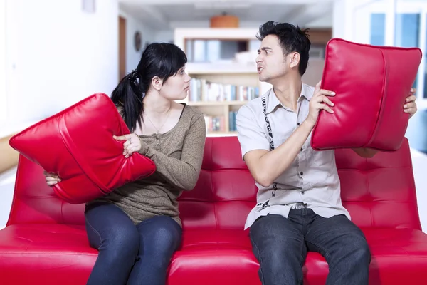 Angry couple on red sofa at home