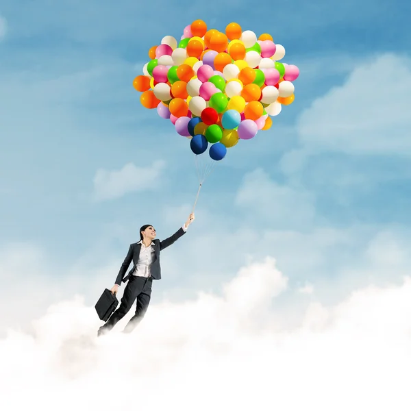 Businesswoman flying with balloons