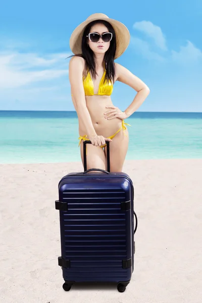 Woman with suitcase standing at beach