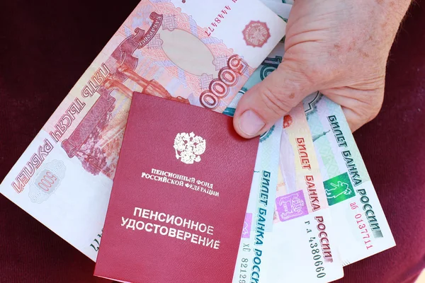 Pension card and money in the hands of an elderly woman