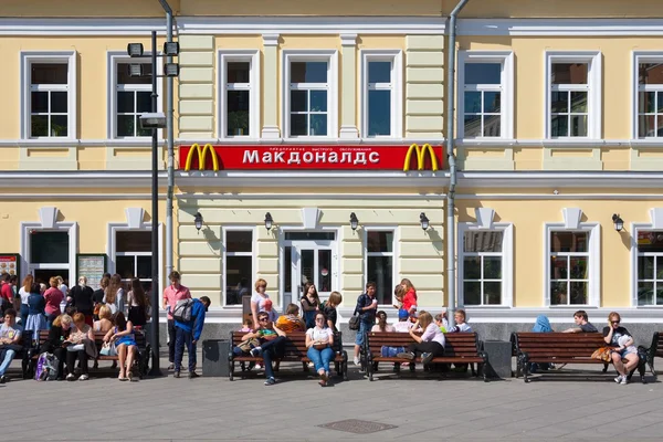 People resting on benches near McDonald's restaurant building