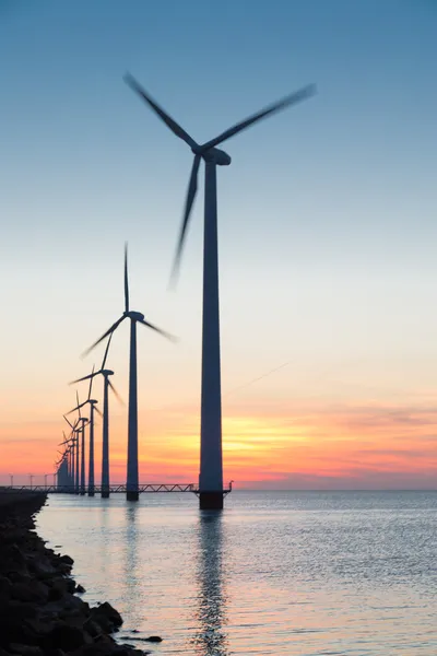 Dutch row offshore wind turbines at beautiful sunset