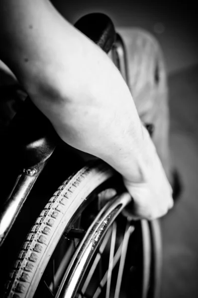 Close-up of male hand on wheel of wheelchair - blac and white
