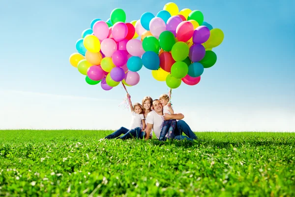 Happy family holding colorful balloons. Mom, ded and two daughte