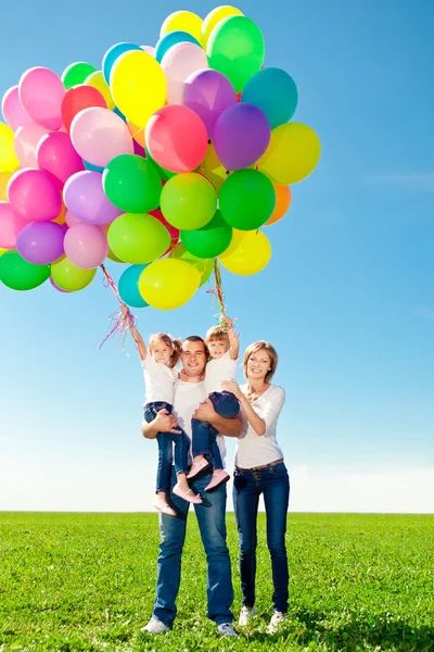 Happy family holding colorful balloons. Mom, ded and two daughte