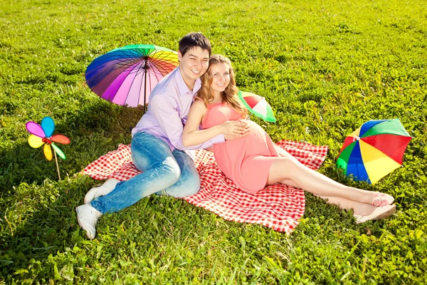 Young healthy beautiful pregnant woman with her husband and rain