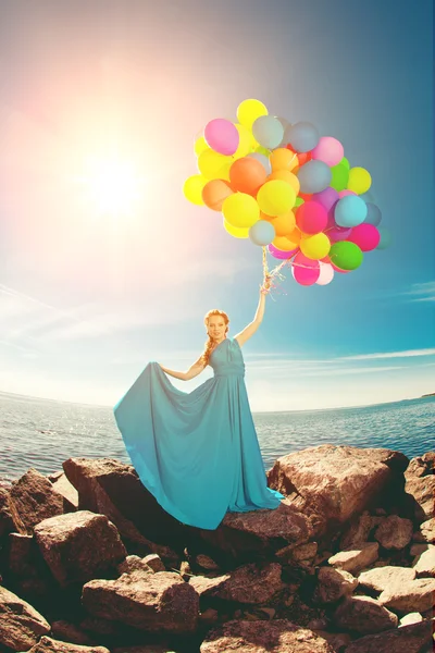 Luxury fashion woman with balloons in hand on the field against