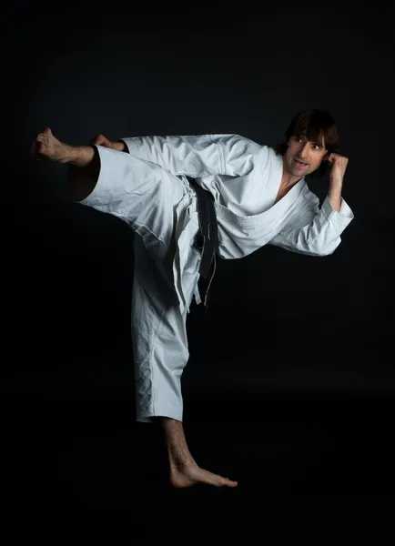 Man doing karate kick with your foot on a black background
