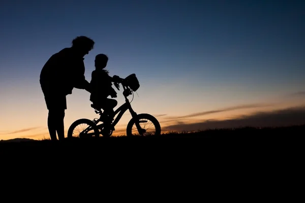 Parent helping a child Learn to Ride A bike