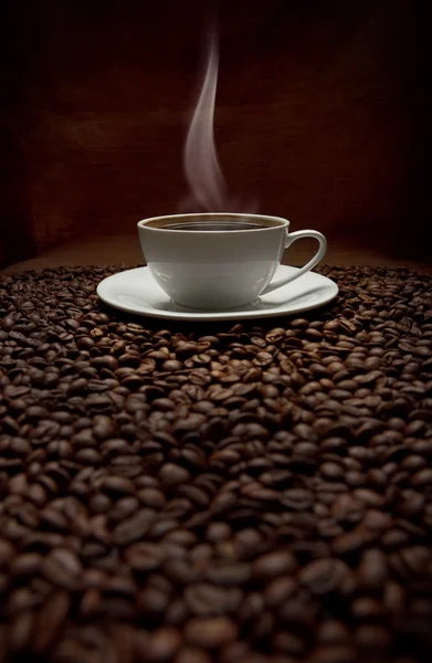 Cup of steaming coffee with beans