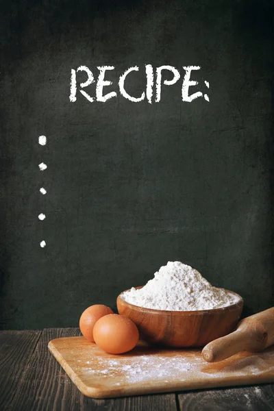 Flour and eggs on a blackboard background. space for recipe