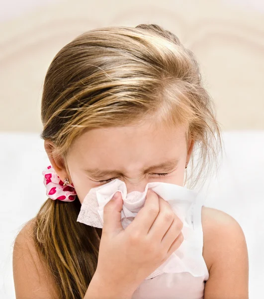 Little girl blowing her nose in a great effort