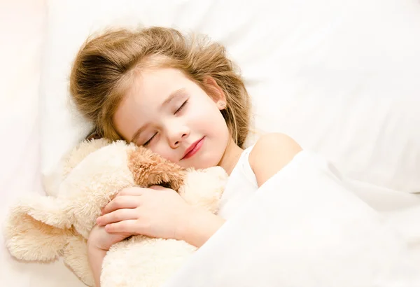 Little girl sleeping in the bed with her toy