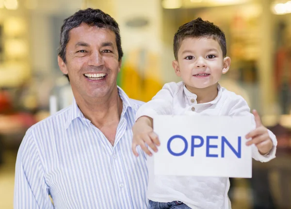 Dad and son holding an open sign