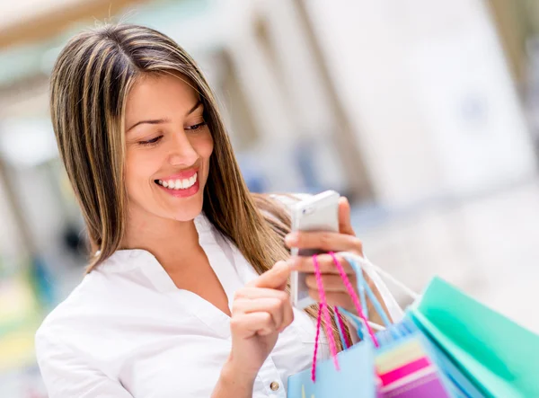 Woman using cell phone while shopping