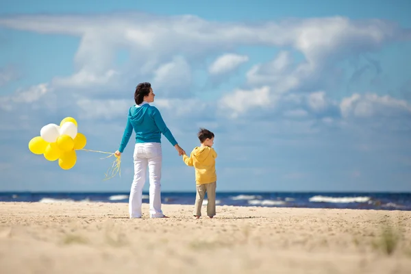 Mother and little son with balloons on the beach
