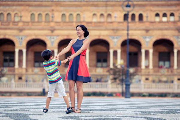 Young mother and her son playing outdoors in city