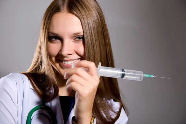 Smiling female doctor with big syringe