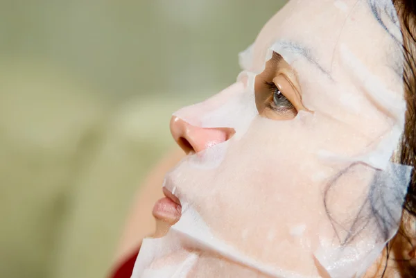 Portrait in Profile woman applying rejuvenating facial mask on h