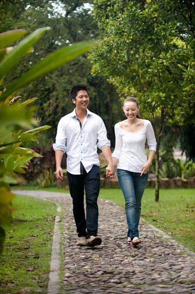 Asian couple holding hands walking on the park path