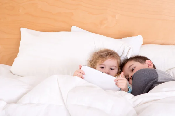 Little brother and sister snuggling up at bedtime