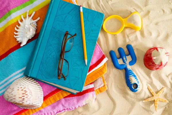 Book and reading glasses on a beach towel