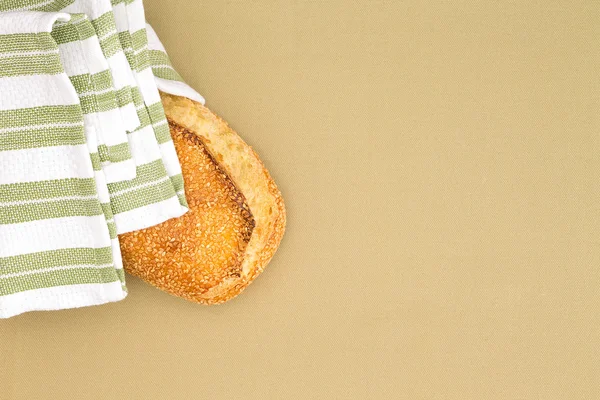 Crusty golden sesame seed loaf in a cloth