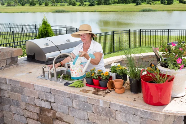 Senior lady filling a watering can on a patio