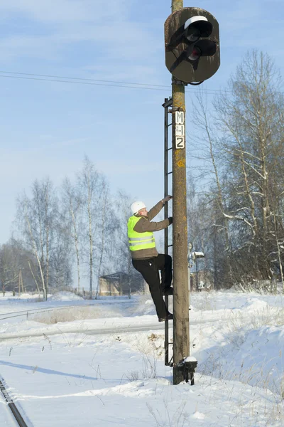 Railroad worker climbing on signal beacons pole