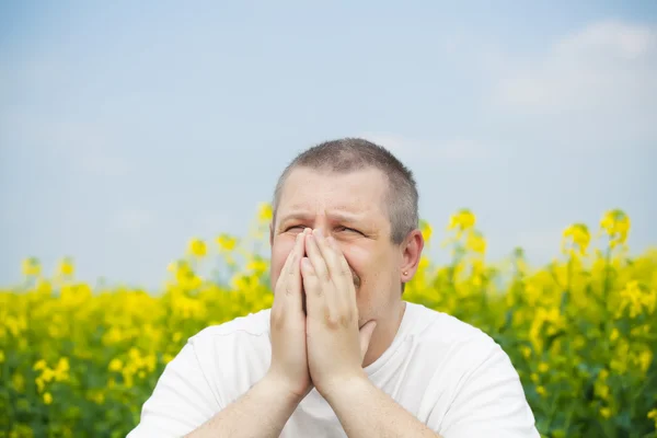 Man keep hands near nose on canola field