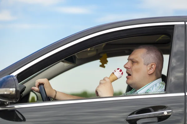 Man eating ice cream while sitting in car