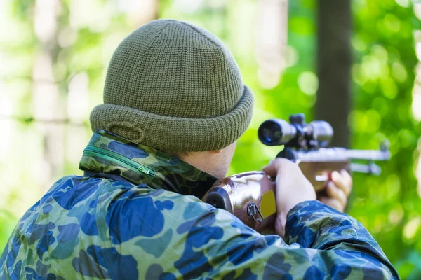 Man with optical rifle in the woods