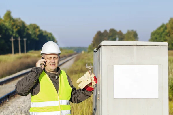 Railroad employee with cell phone near the electrical enclosure